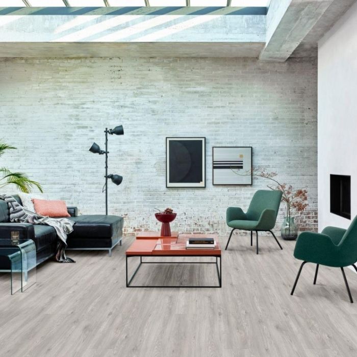 medium grey wood effect rigid click lvt flooring in living room space with natural brick walls and black leather sofa sierra oak 58933