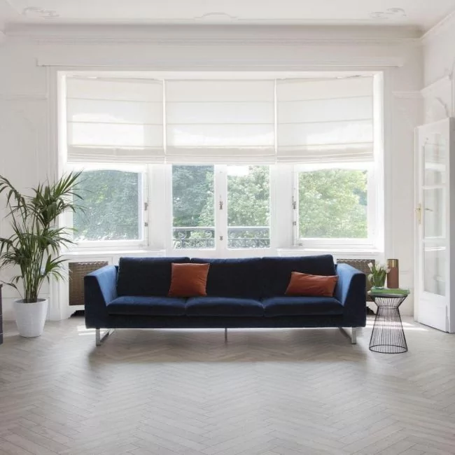 grey wood effect parquet laminate flooring in 8mm thickness with bevelled edges for living room with blue couch and white walls